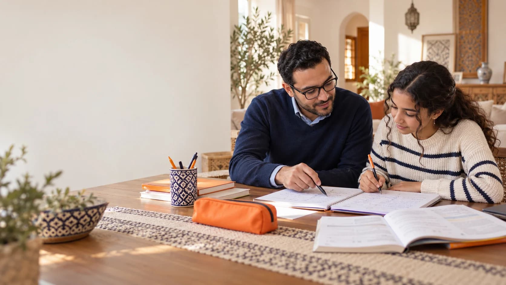 أستاذ يساعد تلميذة على التعلم باستعمال دفترها في المنزل.